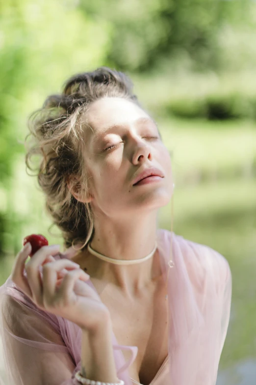 a woman in pink shirt with necklace holding flower