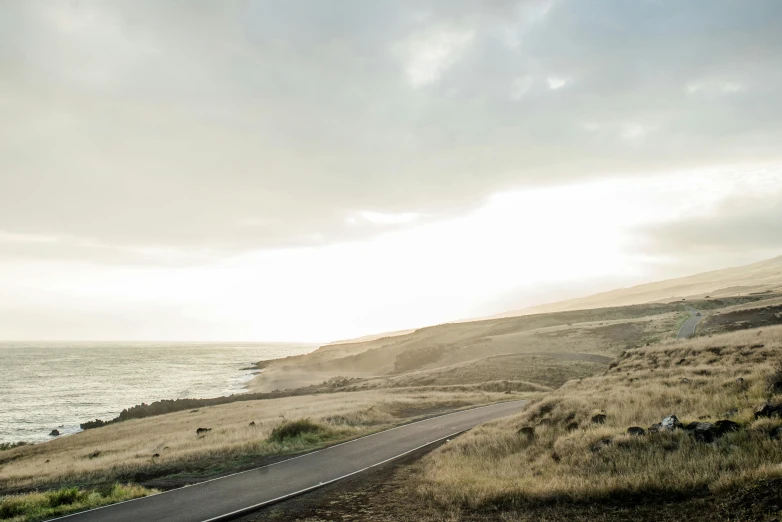 a car driving down the road next to a body of water