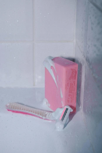 a pink toothbrush is sitting on a soap block