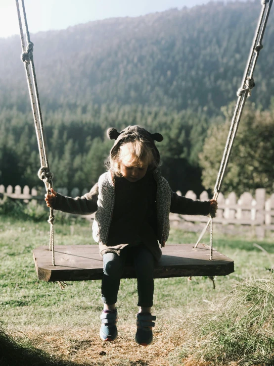 there is a  sitting on a wooden swing