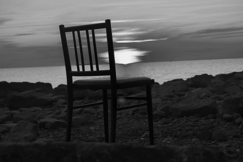 an empty chair on the rocky shore with rocks in the foreground