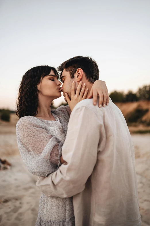 a man kissing a woman on the forehead on a beach