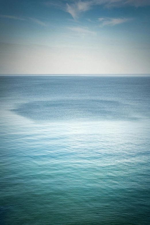 the sky and water with a few clouds over the ocean