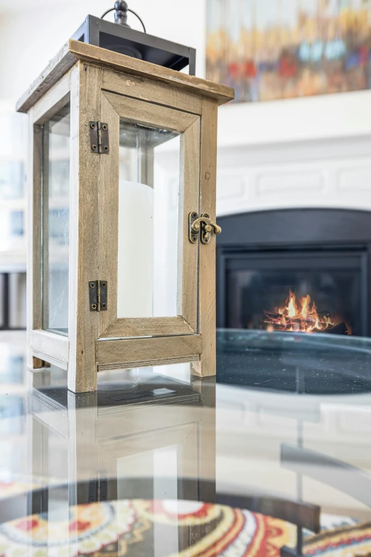 a wooden lantern sitting on top of a table next to a fire place