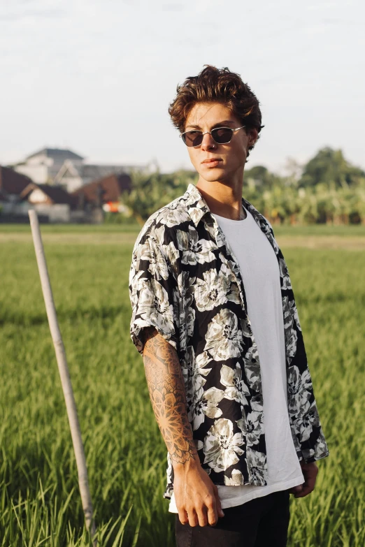 a young man wearing a hawaiian shirt and dark sunglasses