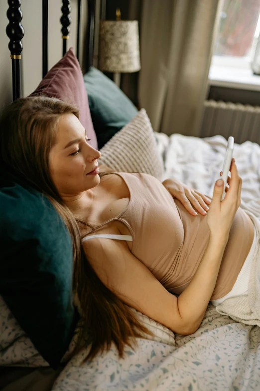 a woman lies on her bed looking at a phone