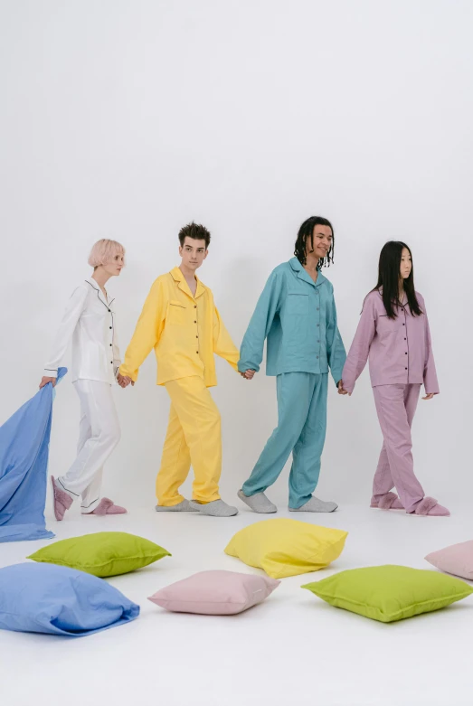 four people standing around some pillows and holding hands