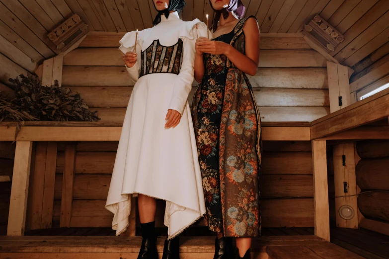 two women wearing unusual outfits standing in front of a wooden wall