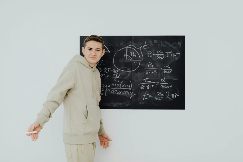 man in white sweatshirt posing in front of blackboard