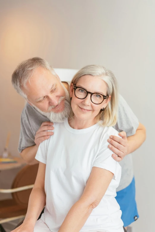 a couple in glasses hug each other as they sit down