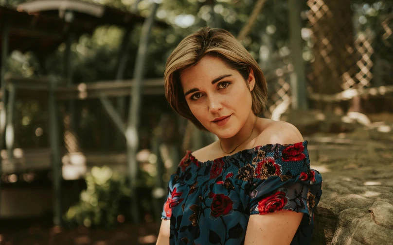 a beautiful woman wearing a blue and red dress sitting on a rock