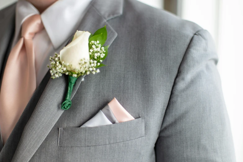 a groom in a gray suit with boutonniere and a flower