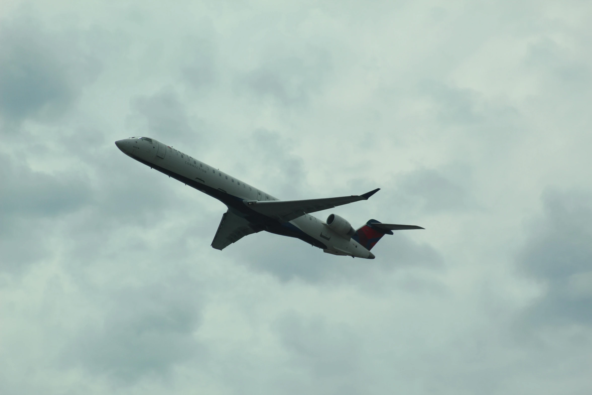 a large jet flying through a cloudy sky