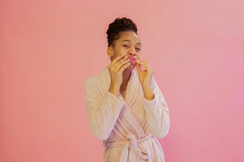 a woman standing on pink has an untucked robe