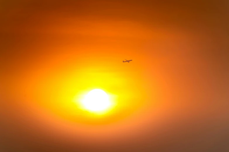 an airplane flying into the sky with a very bright sun in the background