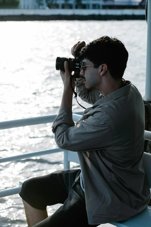 a man sitting on the side of a pier while holding a camera