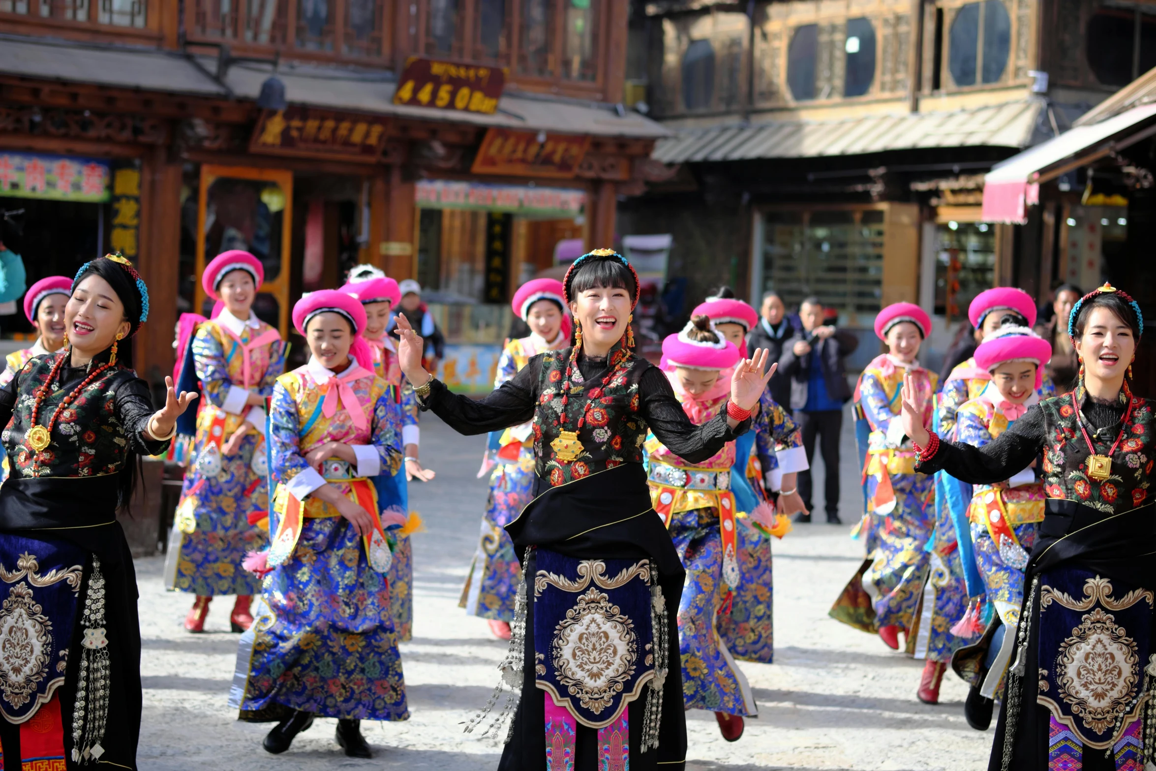 group of women in colorful ethnic clothing holding their arms up