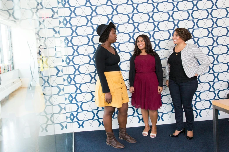 three women posing in front of a wall