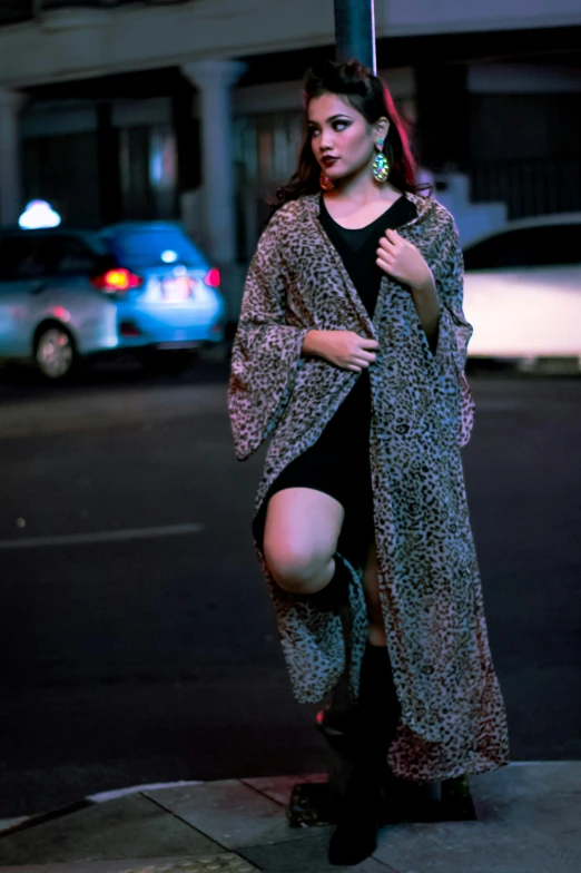 a woman in boots and dress standing on a pole at night