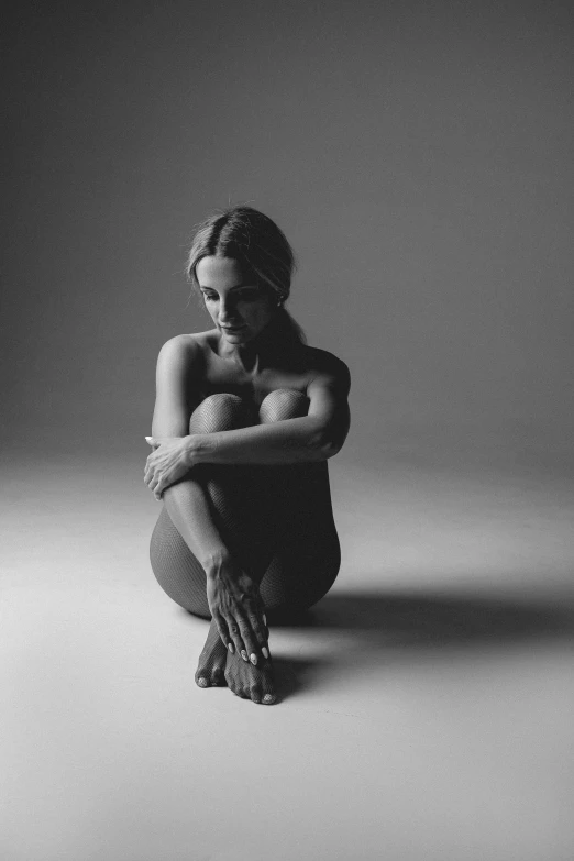 black and white po of a woman crouching and holding her head