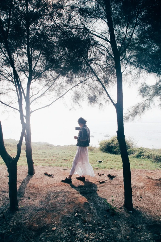 the woman in white dress is standing between trees