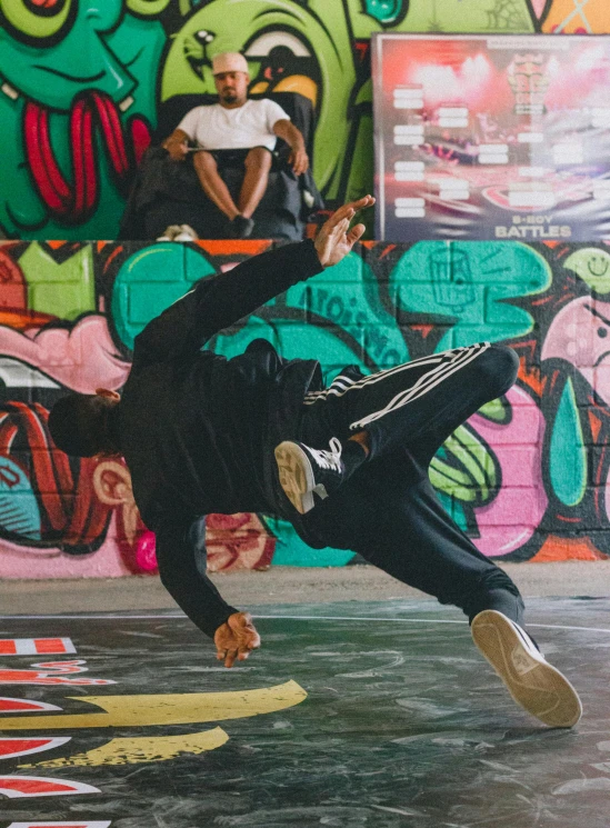 a man is performing a dance move in front of graffiti