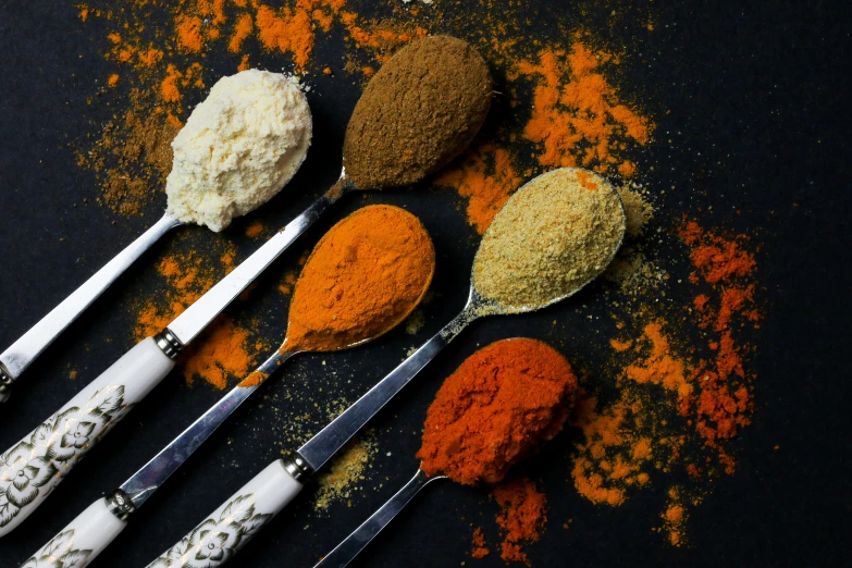 there are several spices in spoons and spices on the table