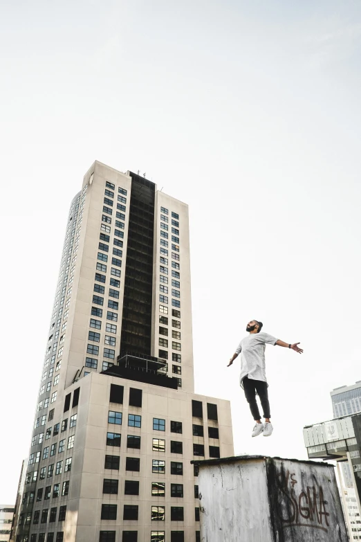 a man on a skateboard jumping off a concrete ledge in front of some skyscrs