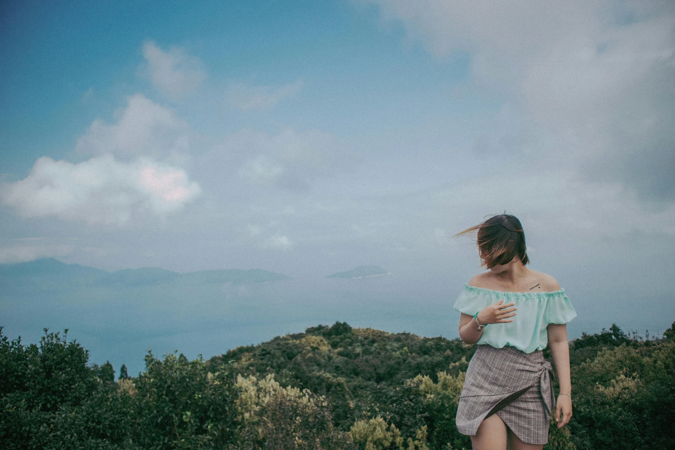 a woman in a short skirt on a hill overlooking the ocean