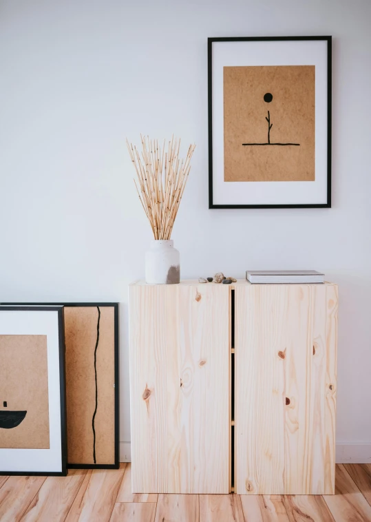 the sideboard is next to a plant and two pictures