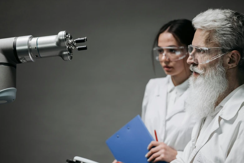 two people are staring at soing in front of a microscope