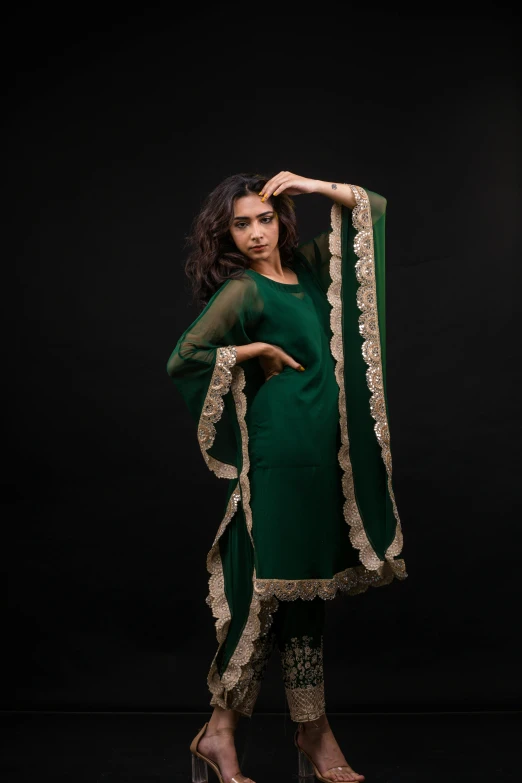 a woman posing in a green outfit with gold details