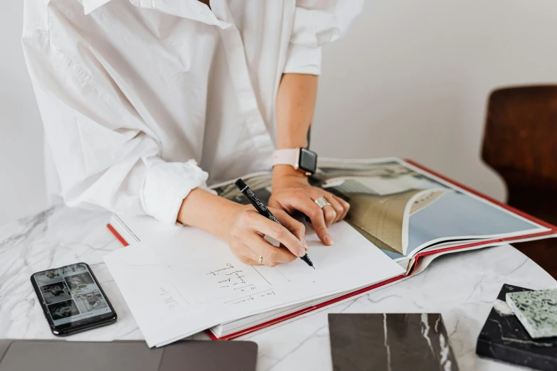 a woman holding a pen and writing in an open notebook