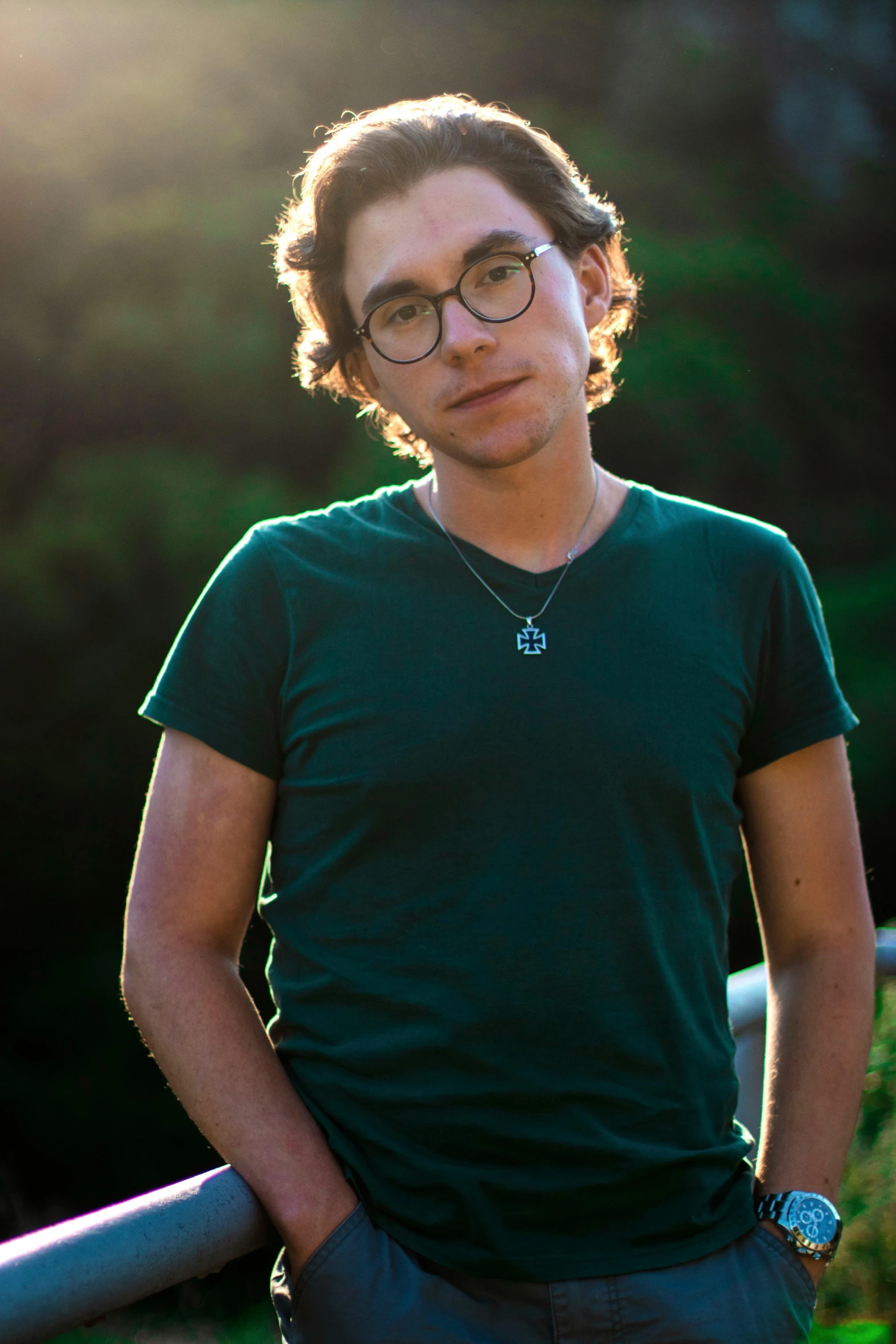 a man with glasses standing next to a metal rail