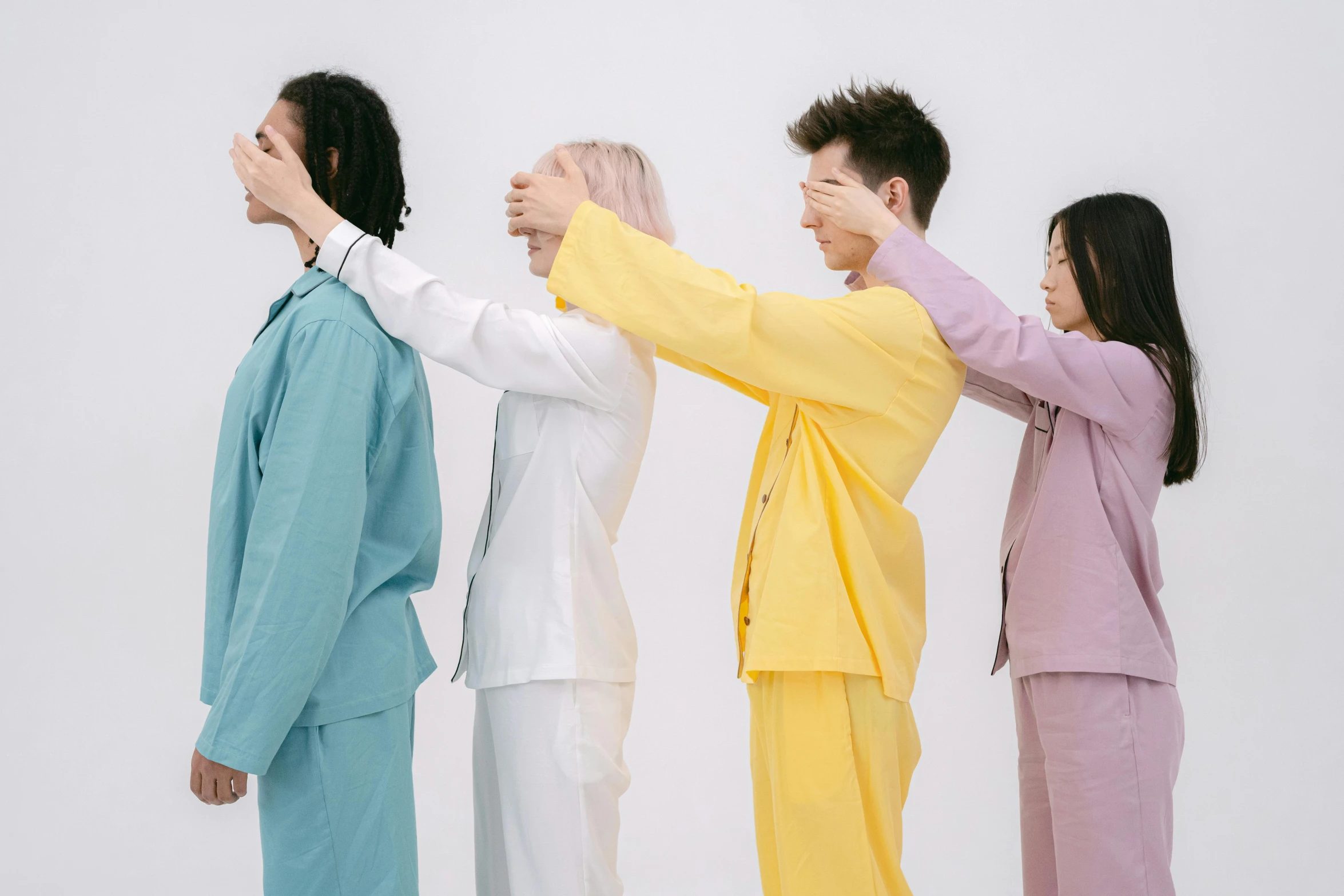 four women in different colors standing in front of a white wall