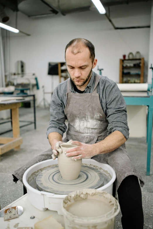 a man with an apron making a vase