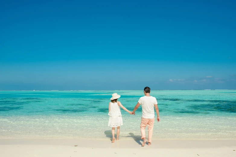 two people walking along the beach holding hands