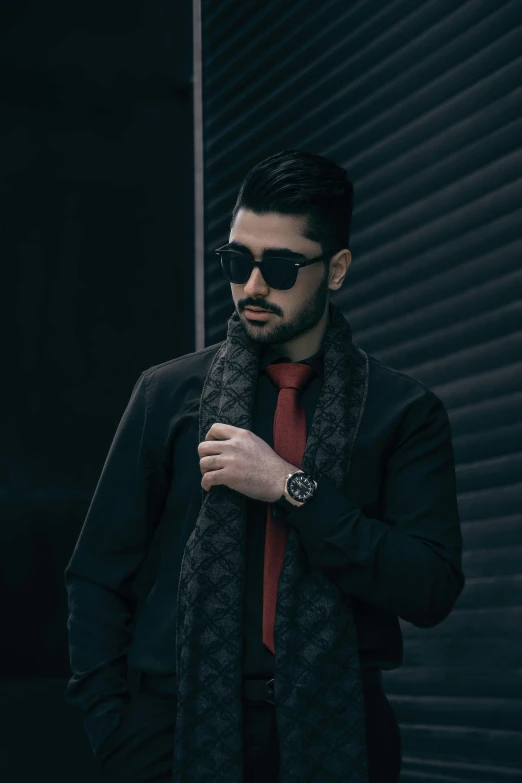 a man with sunglasses, a jacket and tie standing outside