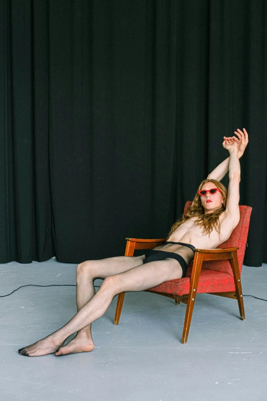 a shirtless man in red and black clothes sitting on a red chair