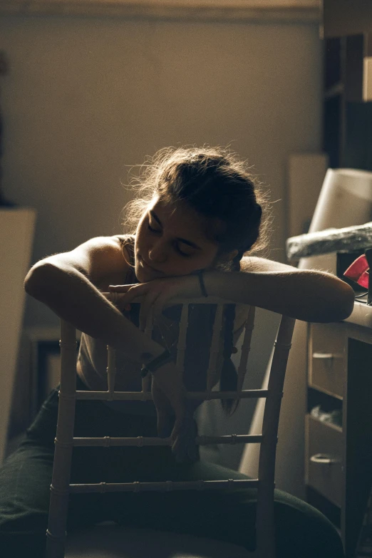 the woman has her shirt down on a wooden chair