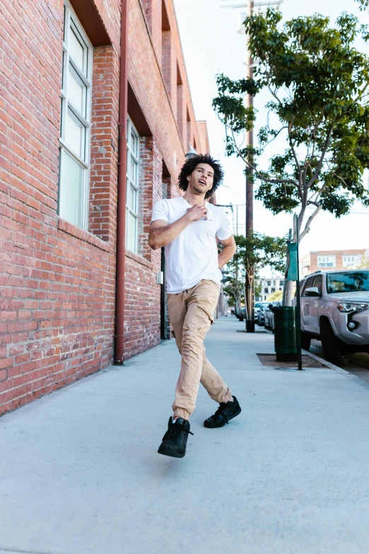 a young man in brown pants and boots is walking