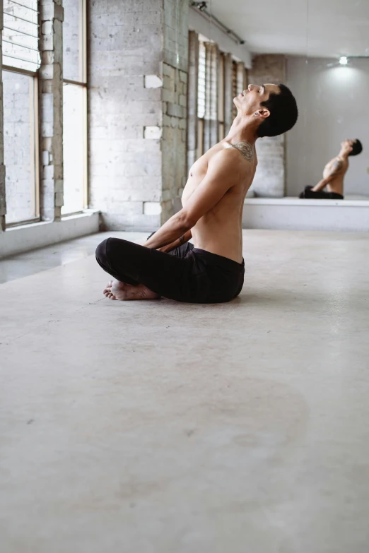 a man doing yoga in a room with windows