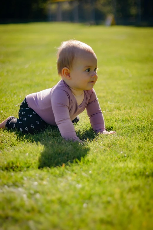 a small baby lies down in the grass