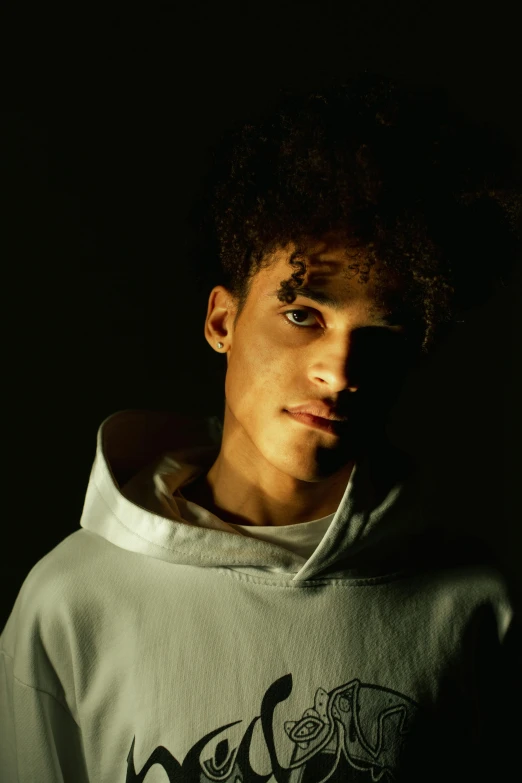 a young man in a hoodie standing up in the dark