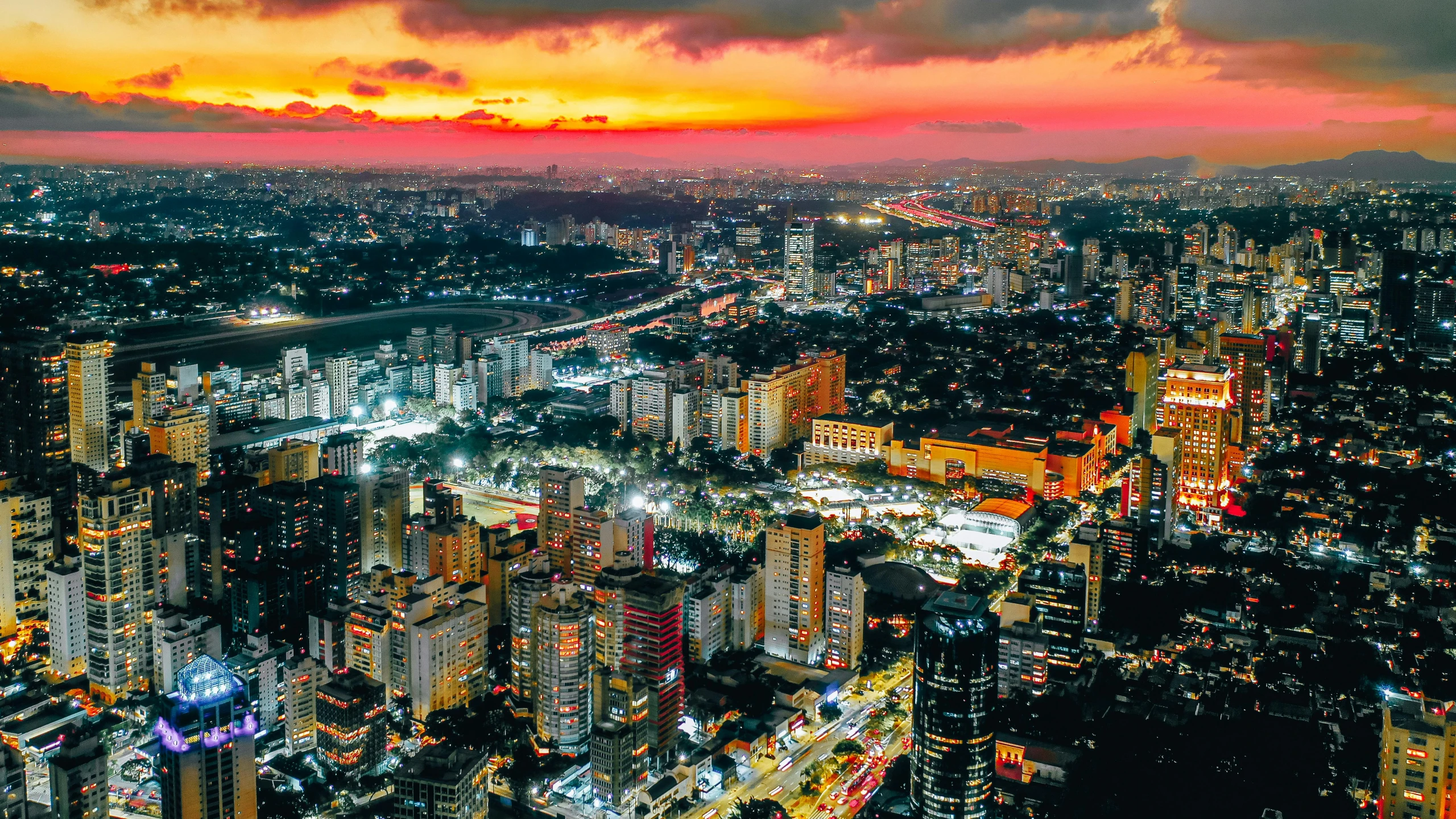 an orange sunset illuminates city lights and skyscrs