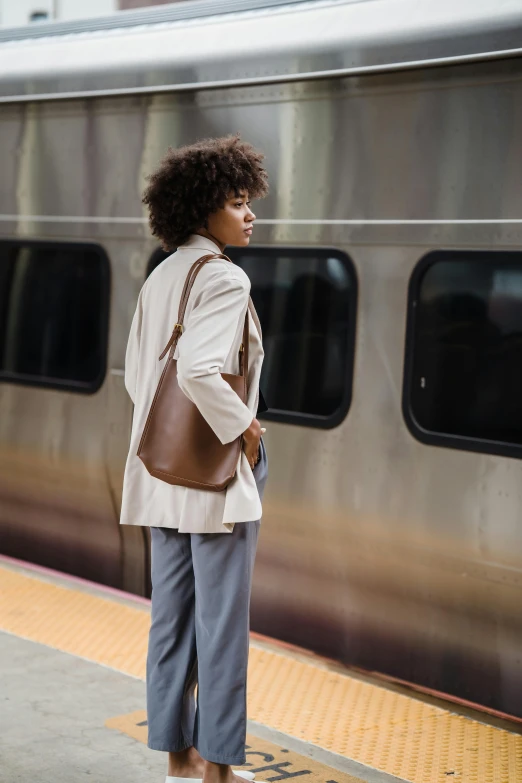 a woman wearing pants stands near a train