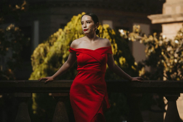 woman in red dress leaning against a wooden railing