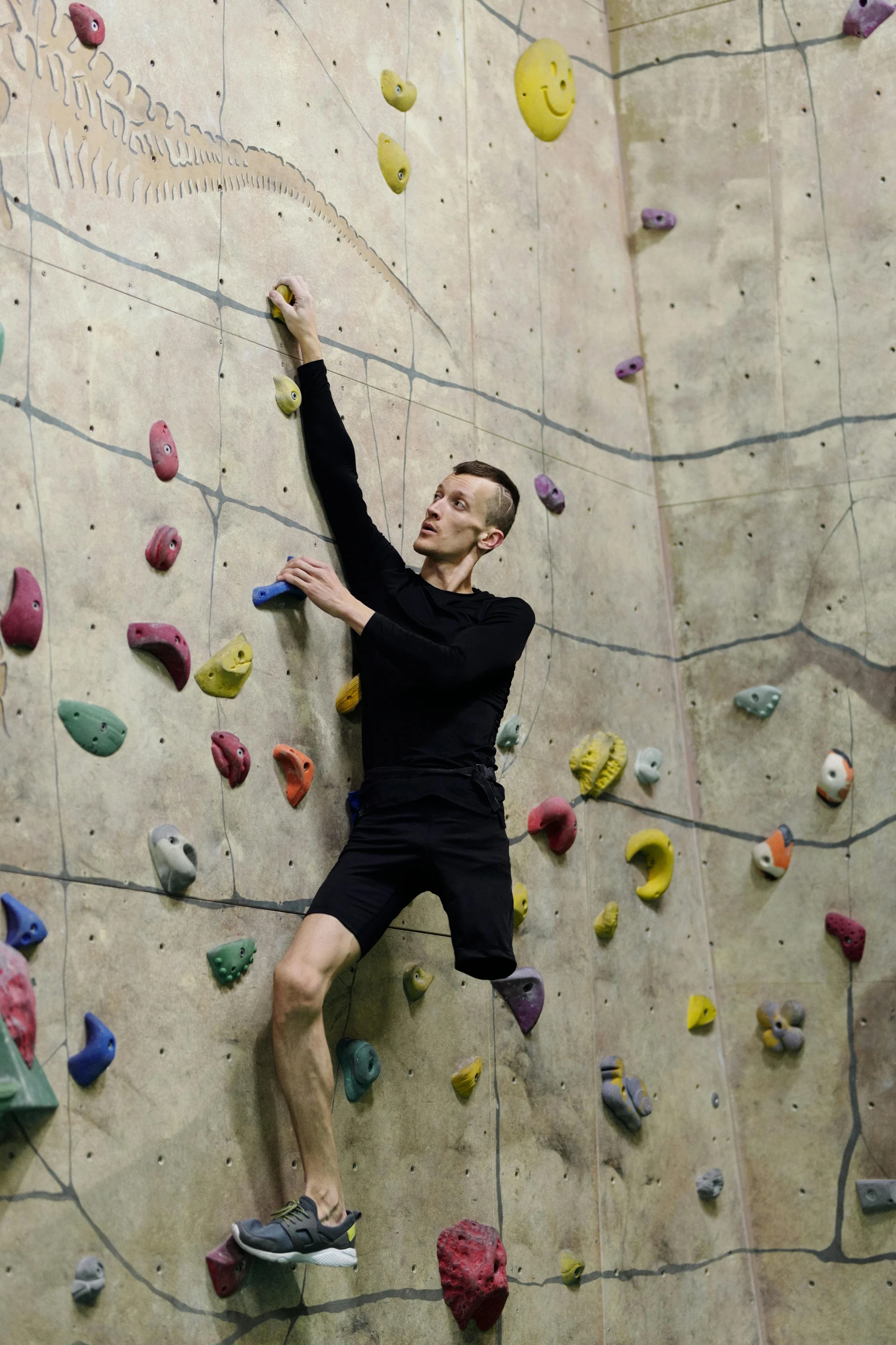 a man in black shirt and shorts climbing on rock wall