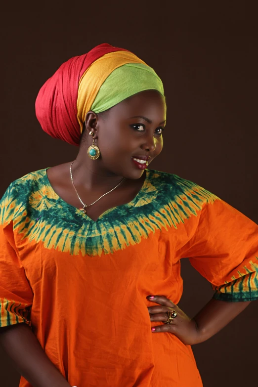 woman in an orange shirt with a colorful tie - dye head scarf on her hair