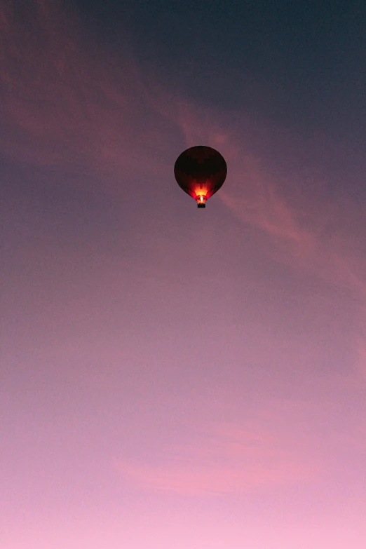 a person sitting at the end of a long bench watching a balloon fly in the sky